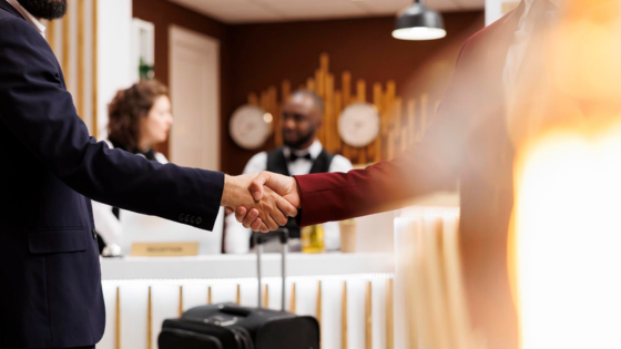 Hóspede em recepção de hotel apertando a mão de atendente durante check-in, representando estratégias de vendas hotel.