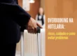 Hóspede com mala na recepção de hotel em imagem sobre overbooking hotel e cuidados para evitar problemas.