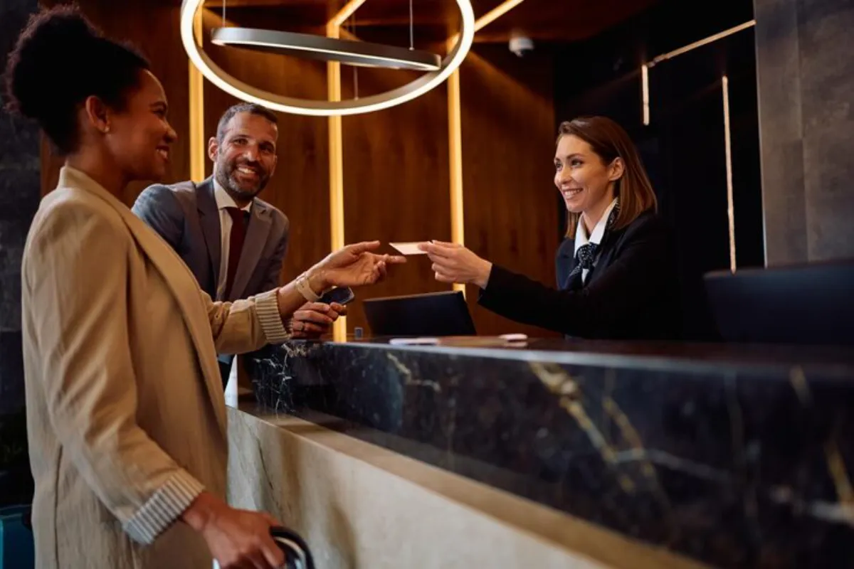 Hóspede recebe atendimento na recepção de hotel durante estratégia de upselling hotel
